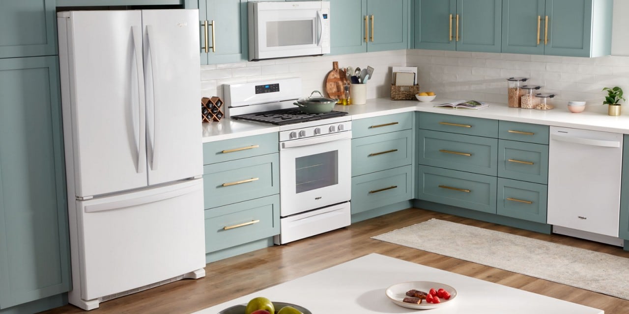 厨房里有一台白色的冰箱、微波炉、烤箱和洗碗机，厨房里有蓝绿色的橱柜