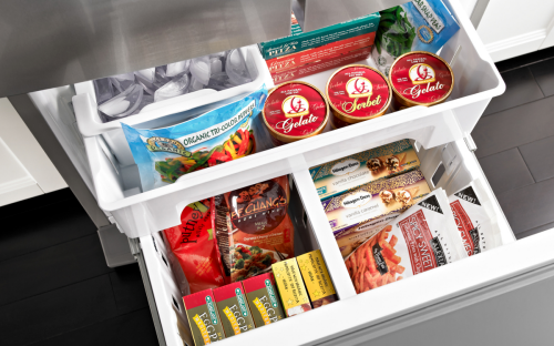 白色的冰箱抽屉打开，里面放着各种冷冻食品