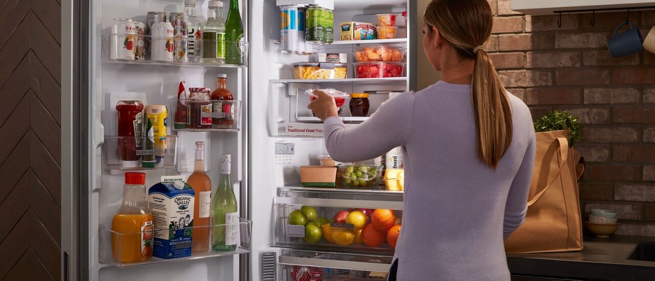 一名妇女将食物装进一个小巧的冰箱