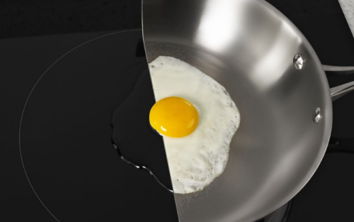 在感应灶台上切成两半的平底锅上煮鸡蛋